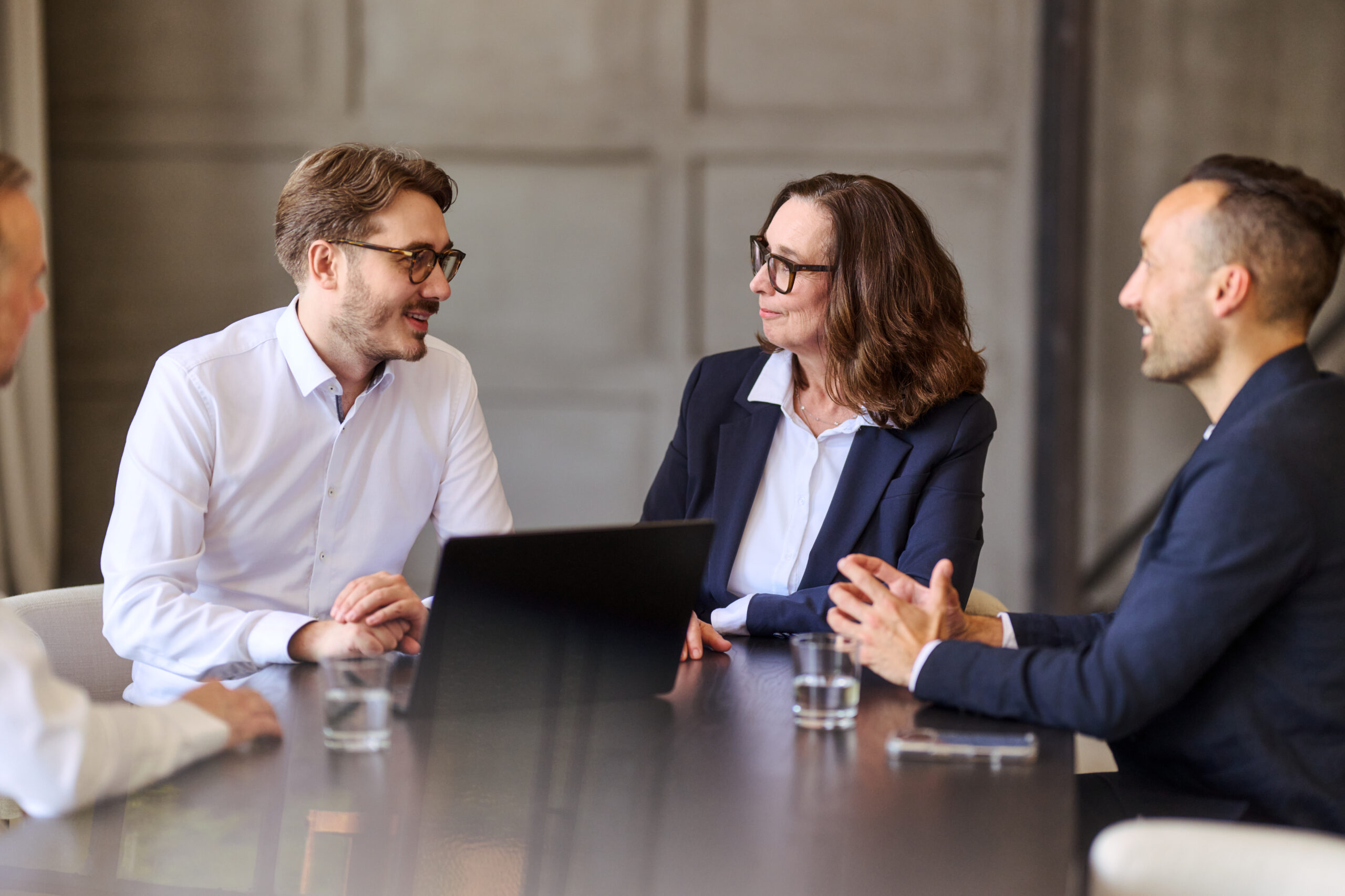 Mitarbeitende sitzen am Tisch mit Laptop
